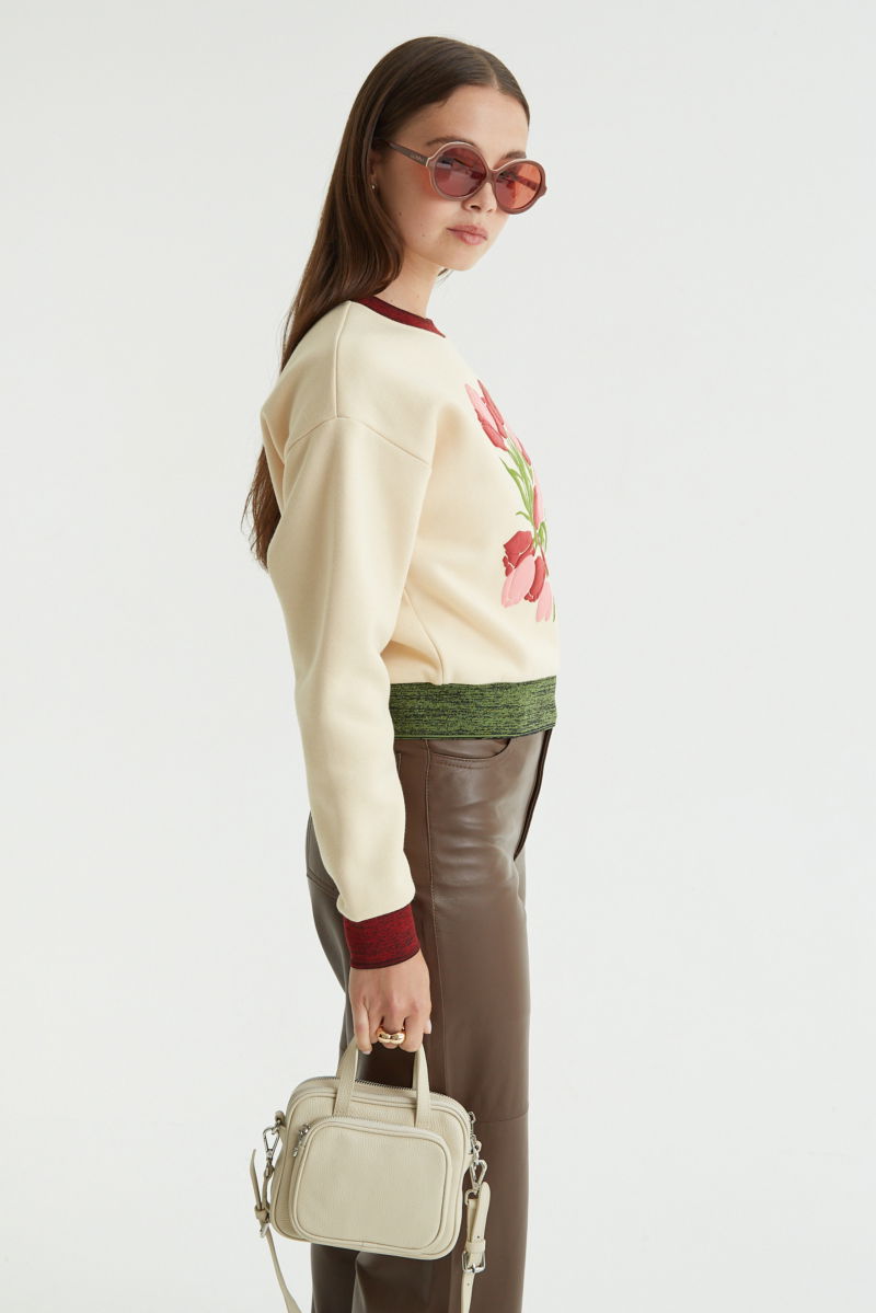 Buzo con estampa de tulipanes en relieve, recto y largo a la cadera con hombros caídos y terminaciones de rib jaspeado a contratono en cuello, puños y ruedo.