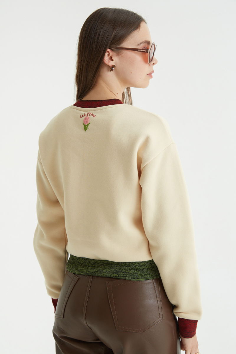 Buzo con estampa de tulipanes en relieve, recto y largo a la cadera con hombros caídos y terminaciones de rib jaspeado a contratono en cuello, puños y ruedo.