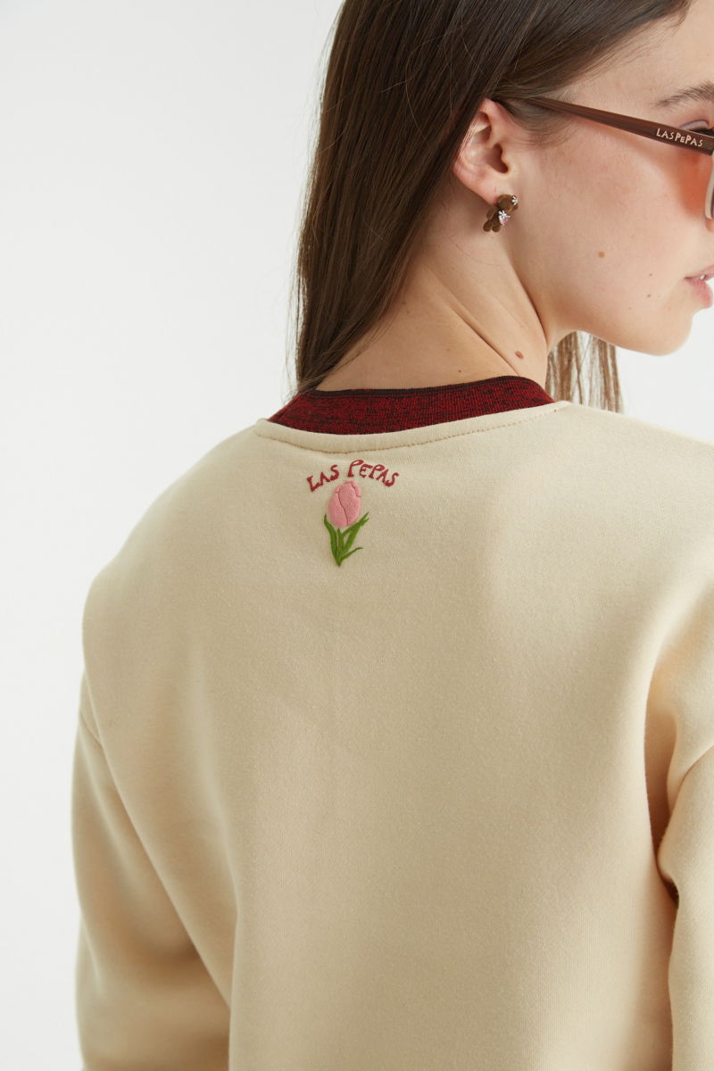 Buzo con estampa de tulipanes en relieve, recto y largo a la cadera con hombros caídos y terminaciones de rib jaspeado a contratono en cuello, puños y ruedo.