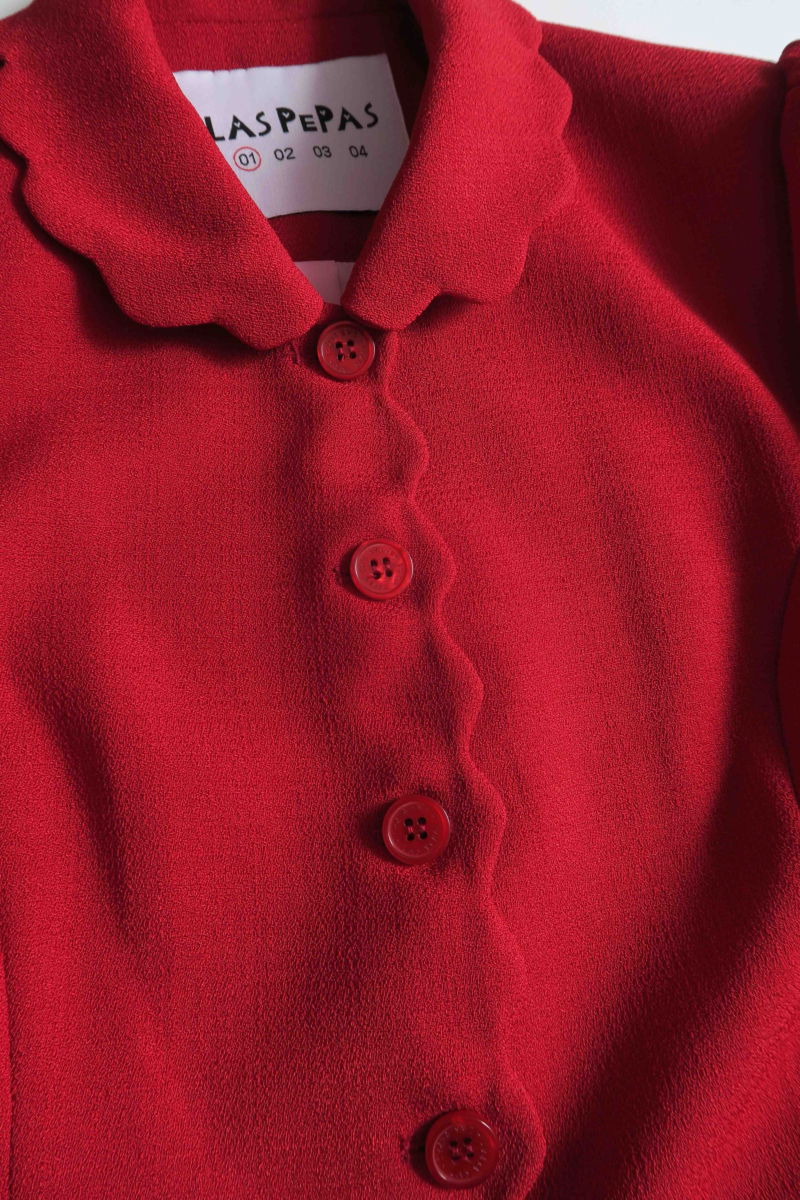 Blazer rojo sastrero entallado con terminación ondulada y mangas princesa. 
