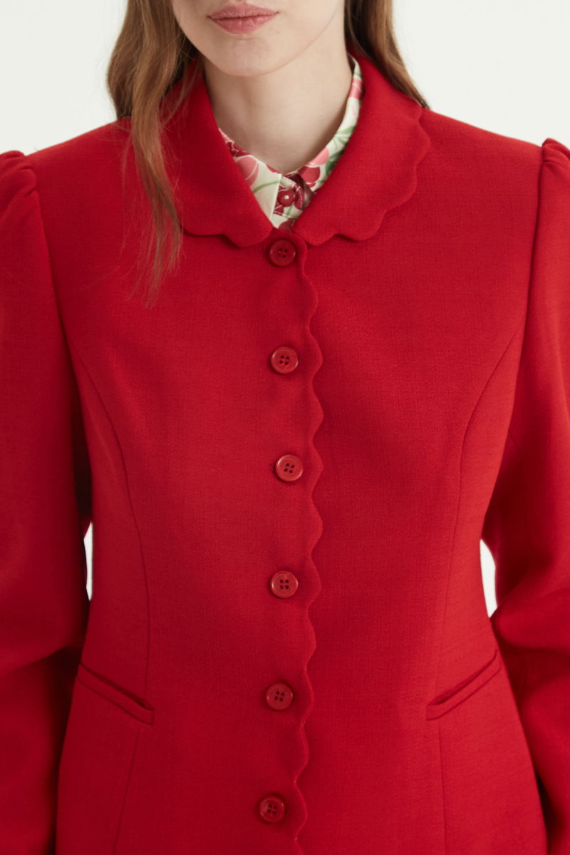 Blazer rojo sastrero entallado con terminación ondulada y mangas princesa. 
