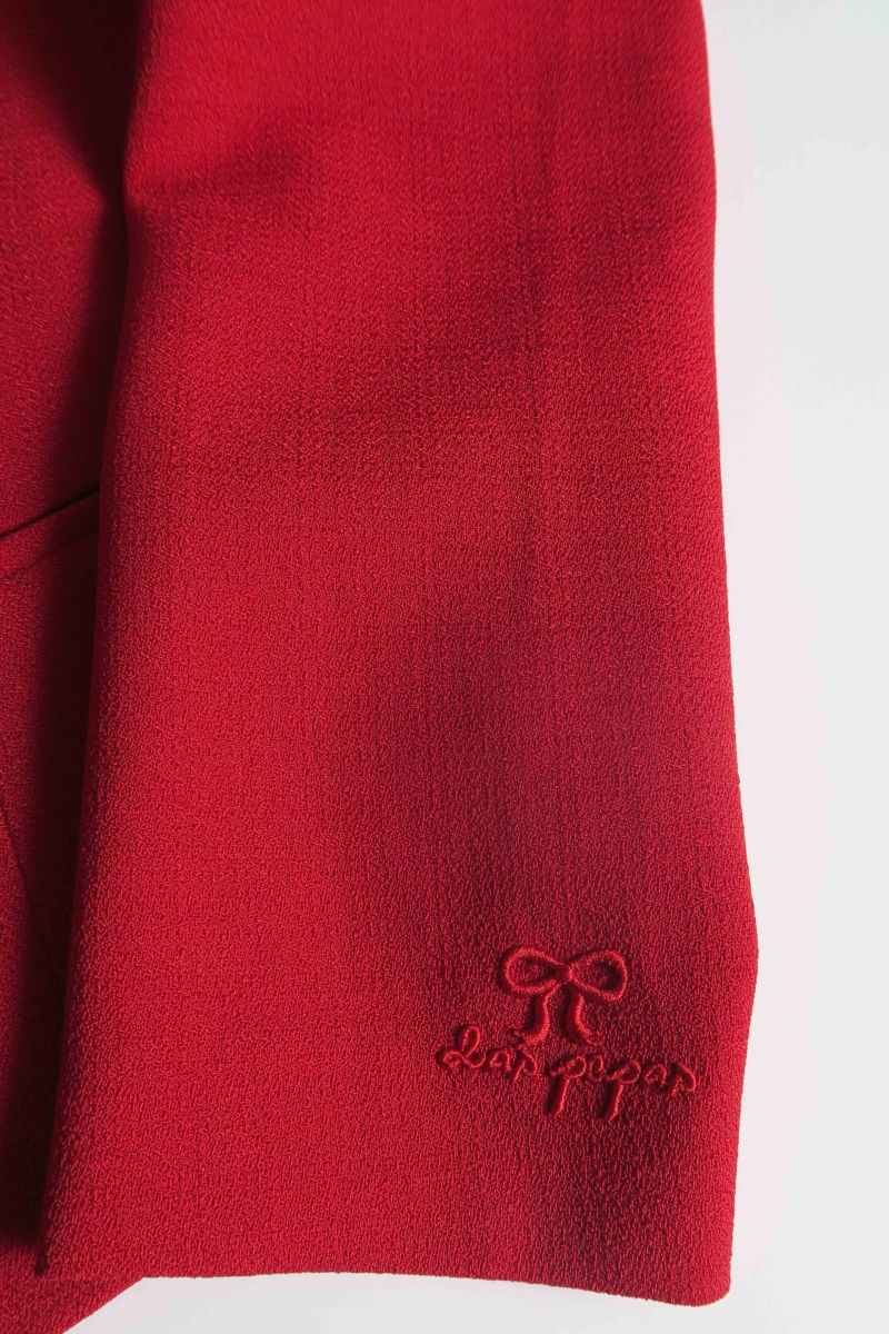 Blazer rojo sastrero entallado con terminación ondulada y mangas princesa. 
