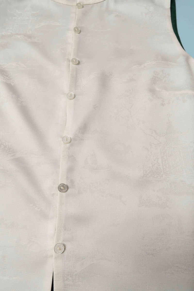 Blusa cruda reversible de jacquard satinado sin mangas con cuello mao, botones a tono, pinzas frontales y aberturas laterales.