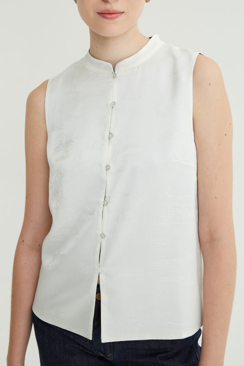 Blusa cruda reversible de jacquard satinado sin mangas con cuello mao, botones a tono, pinzas frontales y aberturas laterales.