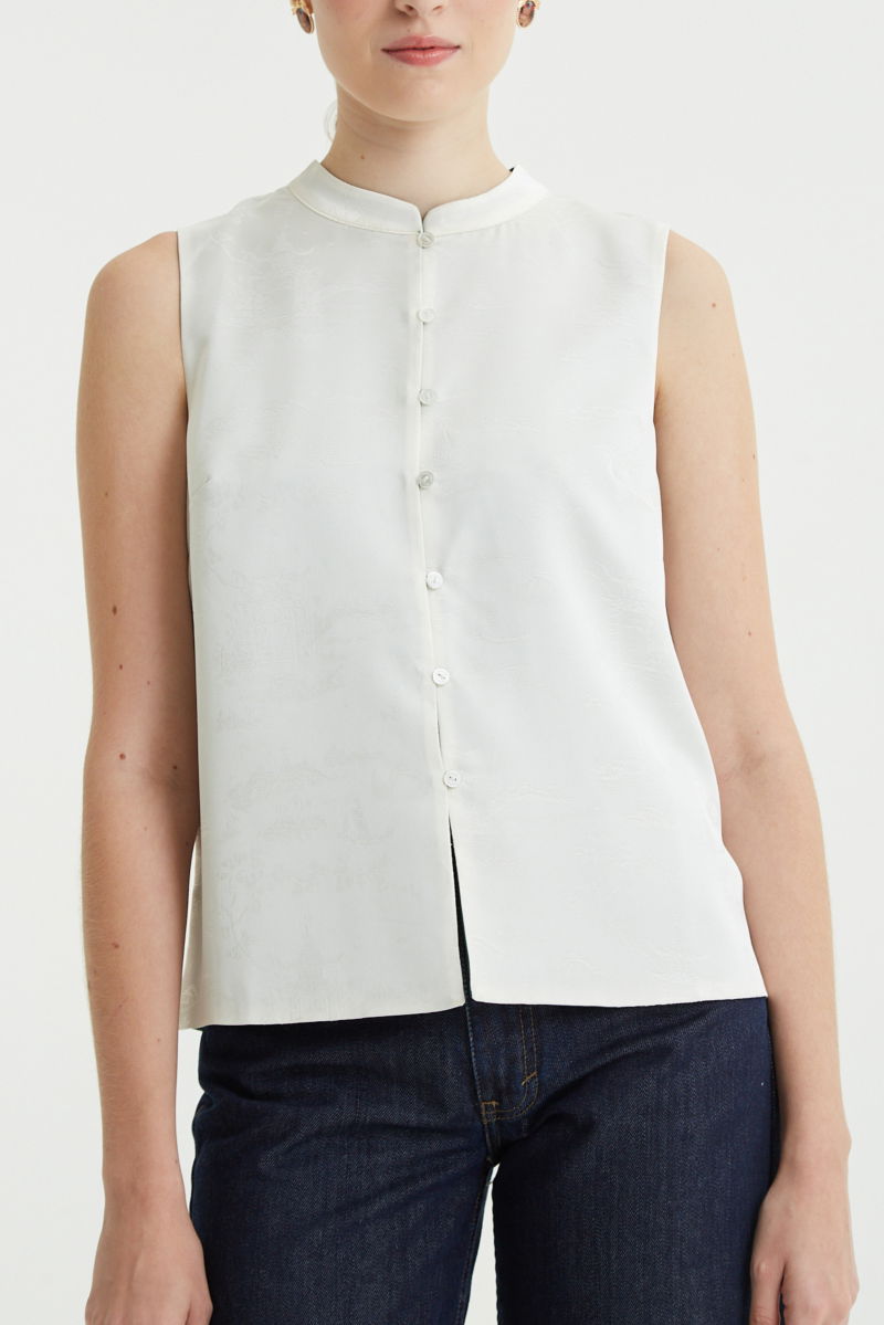 Blusa cruda reversible de jacquard satinado sin mangas con cuello mao, botones a tono, pinzas frontales y aberturas laterales.