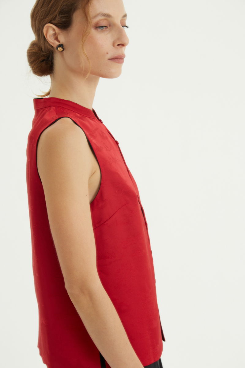 Blusa negra reversible de jacquard satinado sin mangas con cuello mao, botones a tono, pinzas frontales y aberturas laterales.