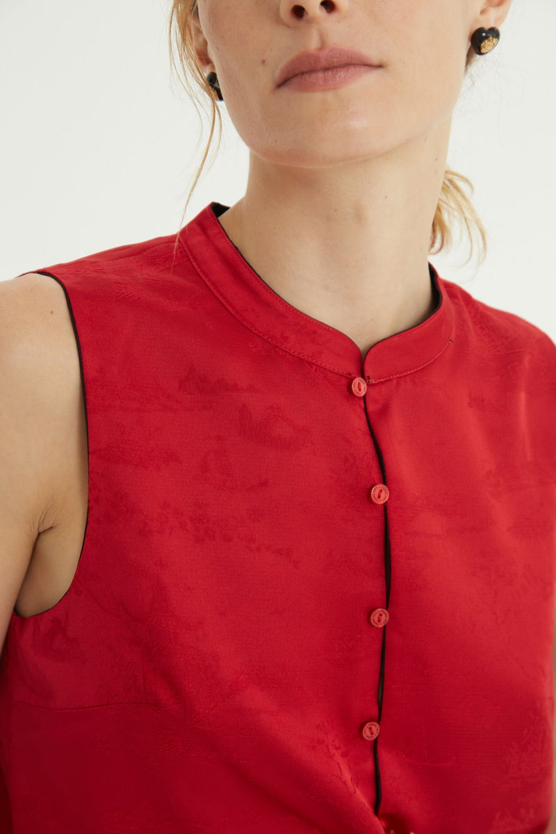 Blusa negra reversible de jacquard satinado sin mangas con cuello mao, botones a tono, pinzas frontales y aberturas laterales.