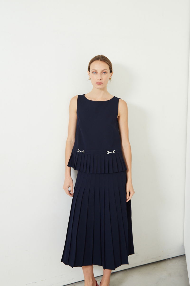 Blusa azul sastrera sin mangas con tablas en la cintura, herrajes metálicos y escote a la base del cuello, larga a la cadera. 