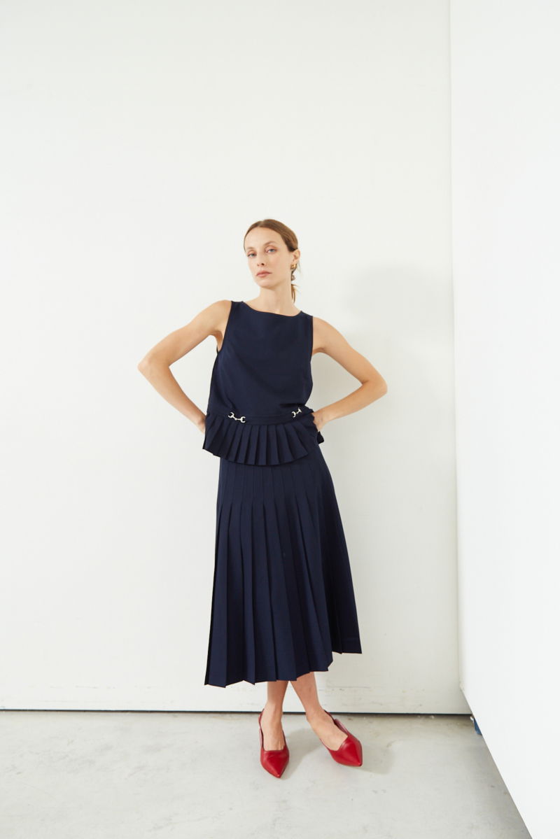 Falda azul sastrera midi de corte evasé y tiro alto con herrajes metálicos en la cintura. 