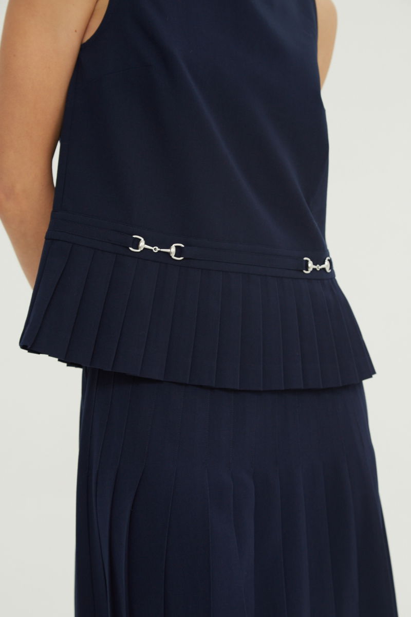 Blusa azul sastrera sin mangas con tablas en la cintura, herrajes metálicos y escote a la base del cuello, larga a la cadera. 