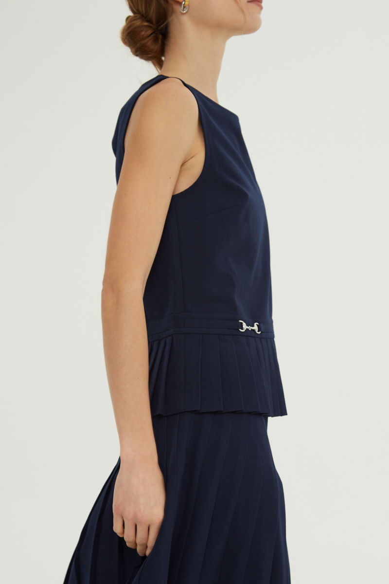 Blusa azul sastrera sin mangas con tablas en la cintura, herrajes metálicos y escote a la base del cuello, larga a la cadera. 