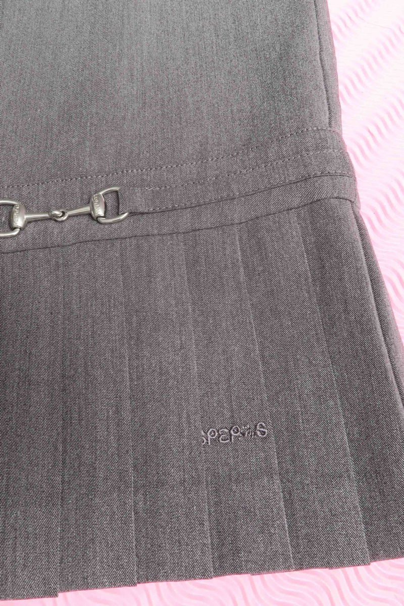 Blusa gris sastrera sin mangas con tablas en la cintura, herrajes metálicos y escote a la base del cuello, larga a la cadera. 