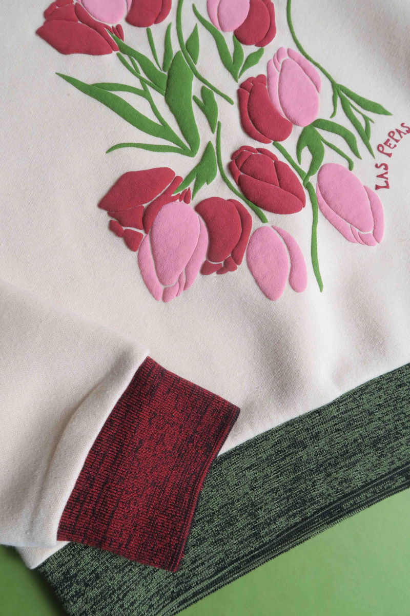 Buzo con estampa de tulipanes en relieve, recto y largo a la cadera con hombros caídos y terminaciones de rib jaspeado a contratono en cuello, puños y ruedo.