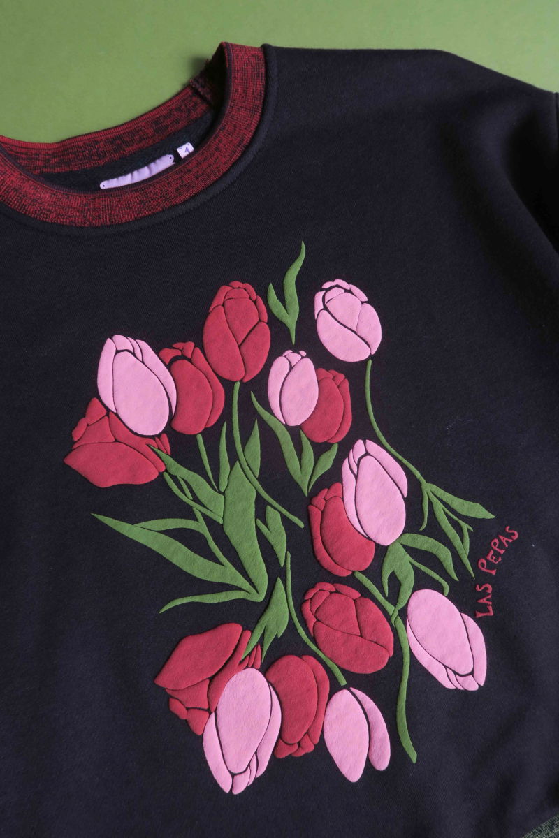 Buzo con estampa de tulipanes en relieve, recto y largo a la cadera con hombros caídos y terminaciones de rib jaspeado a contratono en cuello, puños y ruedo.