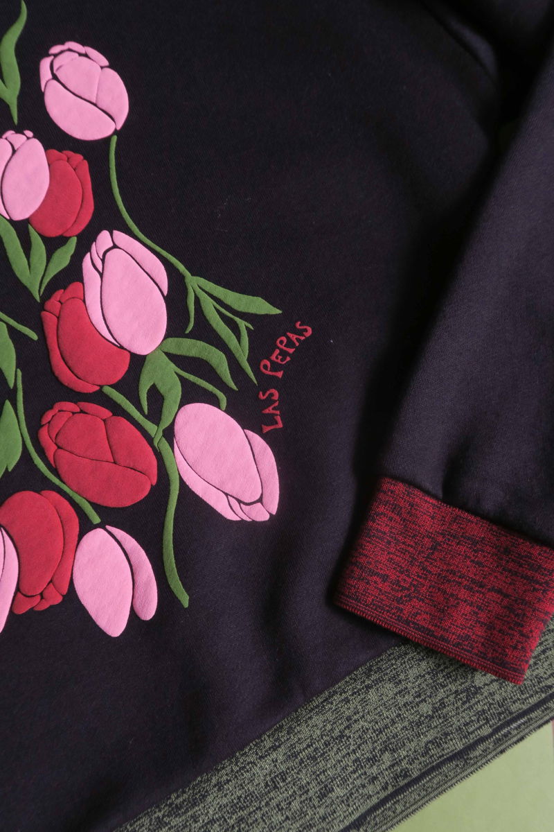 Buzo con estampa de tulipanes en relieve, recto y largo a la cadera con hombros caídos y terminaciones de rib jaspeado a contratono en cuello, puños y ruedo.