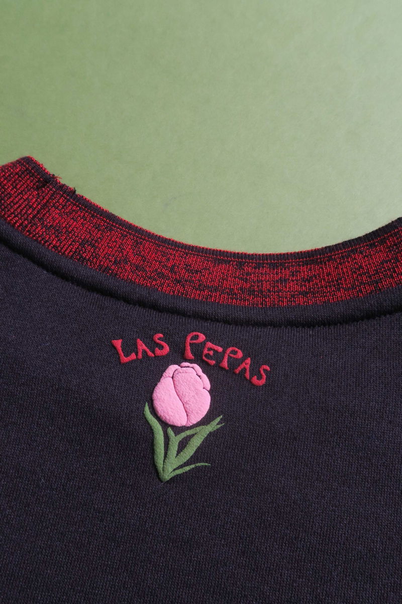 Buzo con estampa de tulipanes en relieve, recto y largo a la cadera con hombros caídos y terminaciones de rib jaspeado a contratono en cuello, puños y ruedo.