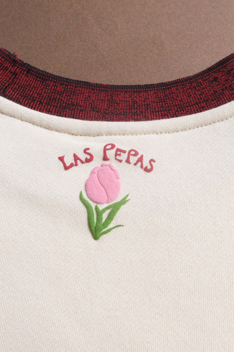 Buzo con estampa de tulipanes en relieve, recto y largo a la cadera con hombros caídos y terminaciones de rib jaspeado a contratono en cuello, puños y ruedo.