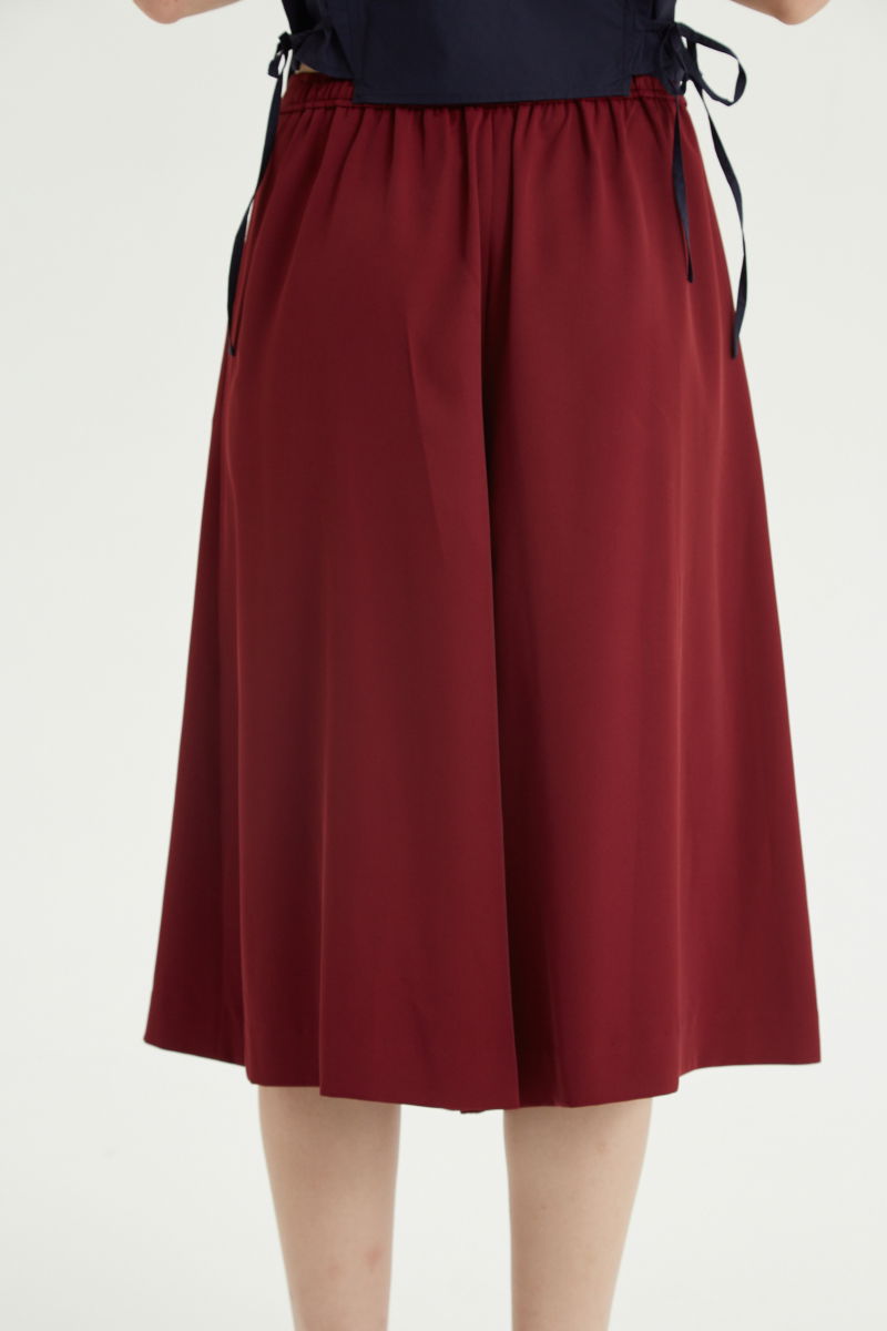 Bermuda bordo sastrera tiro medio con piernas anchas hasta la rodilla, cintura trasera con elástico, tablas y bolsillos laterales. 