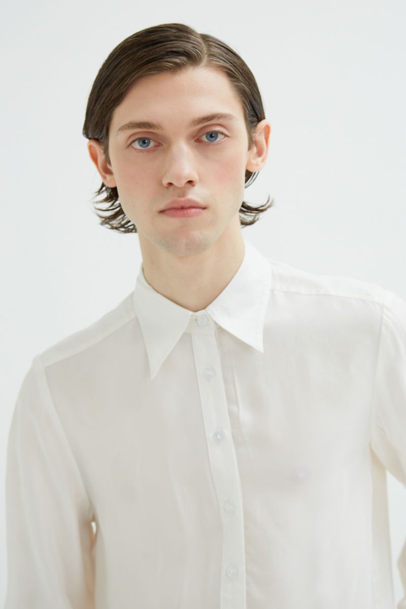 Camisa blanca de calce recto y puños anchos con textura suave de piel de durazno. 
