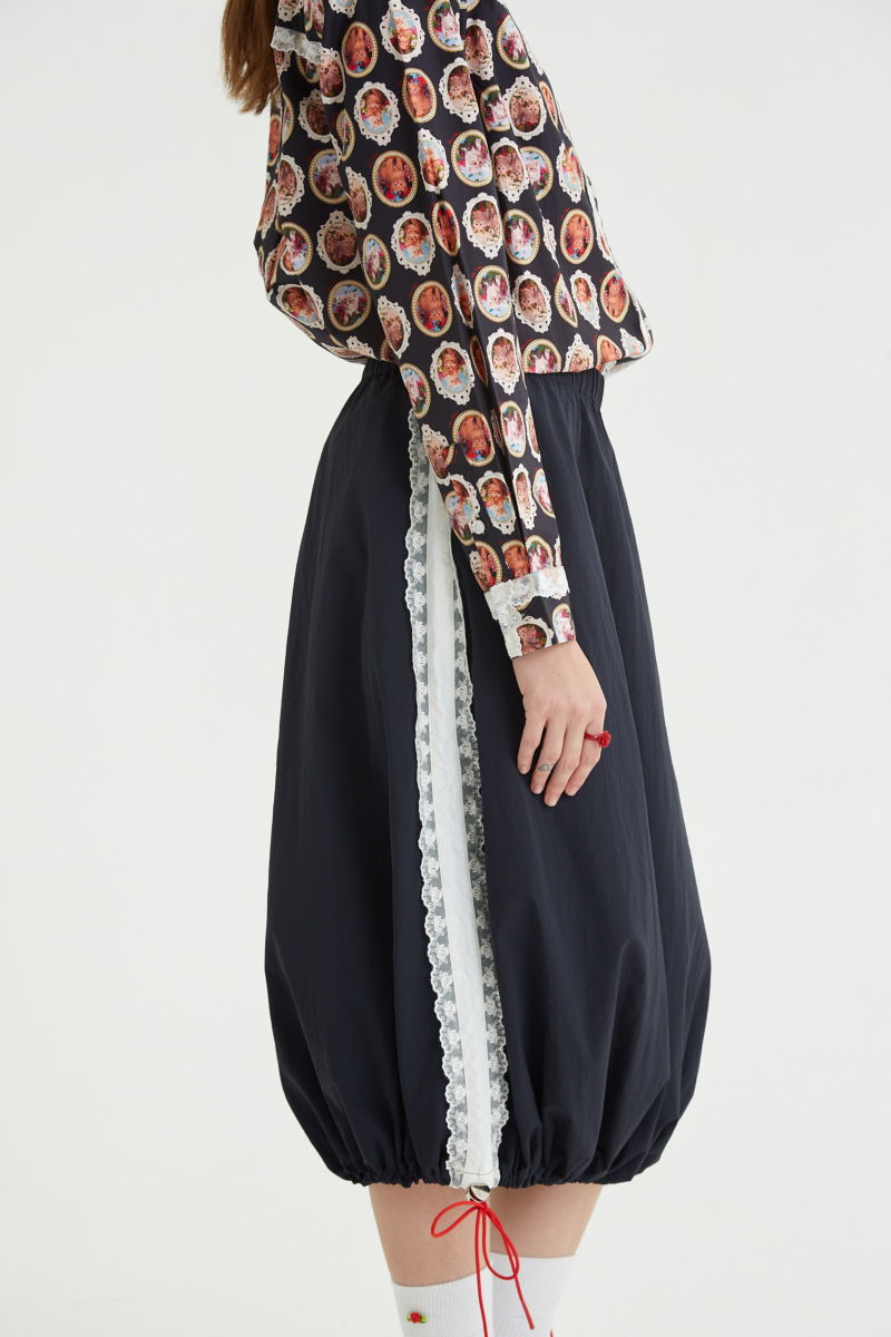 Falda midi recta con cintura elastizada, puntilla en los laterales y ruedo regulable con elástico y tancas. 