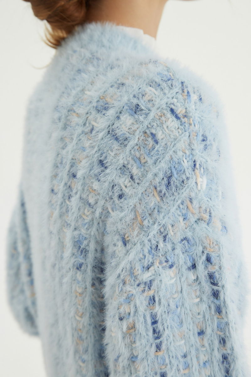 Saco tejido multicolor con textura de pelo y botones perlados en forma de flor. 
