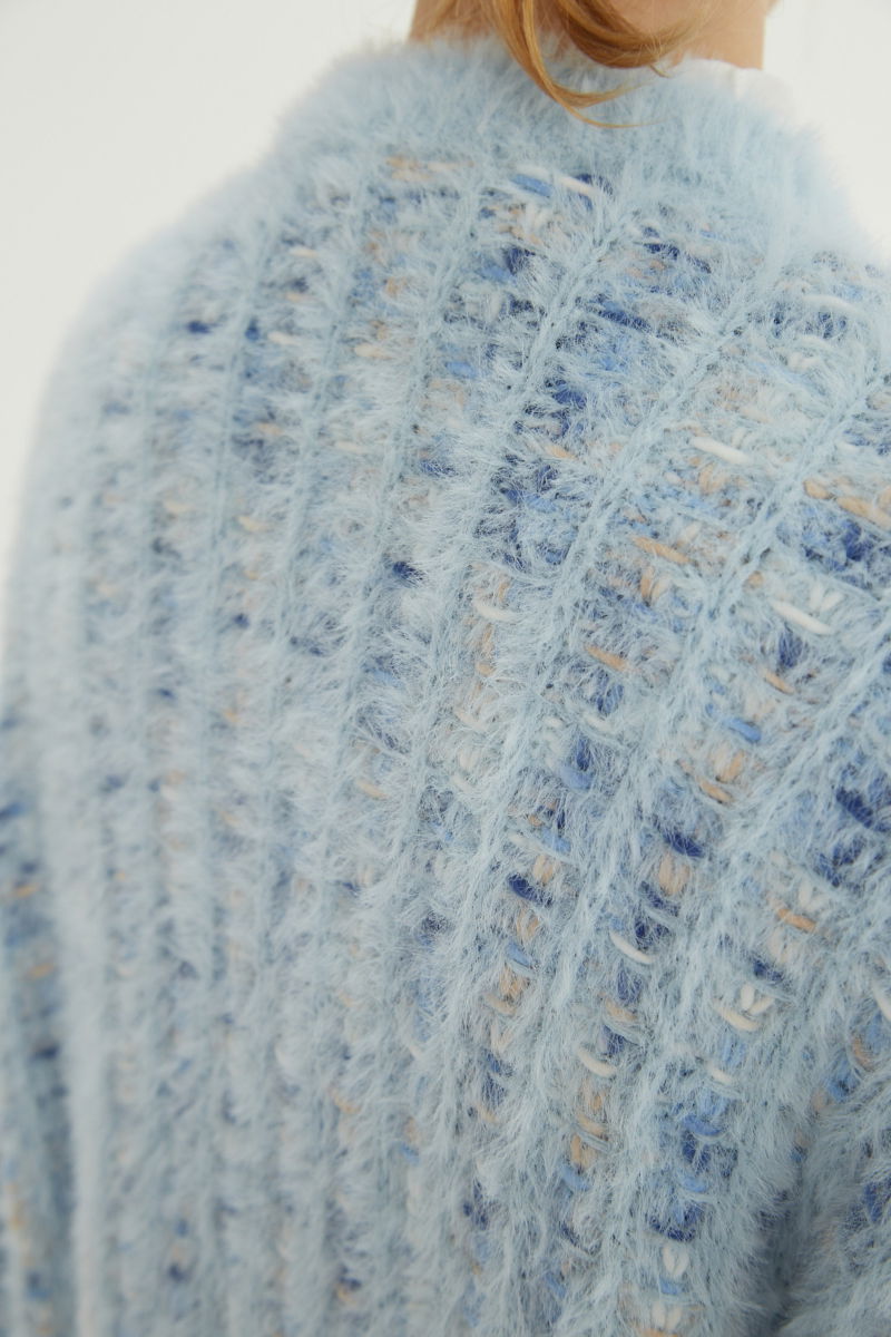 Saco tejido multicolor con textura de pelo y botones perlados en forma de flor. 
