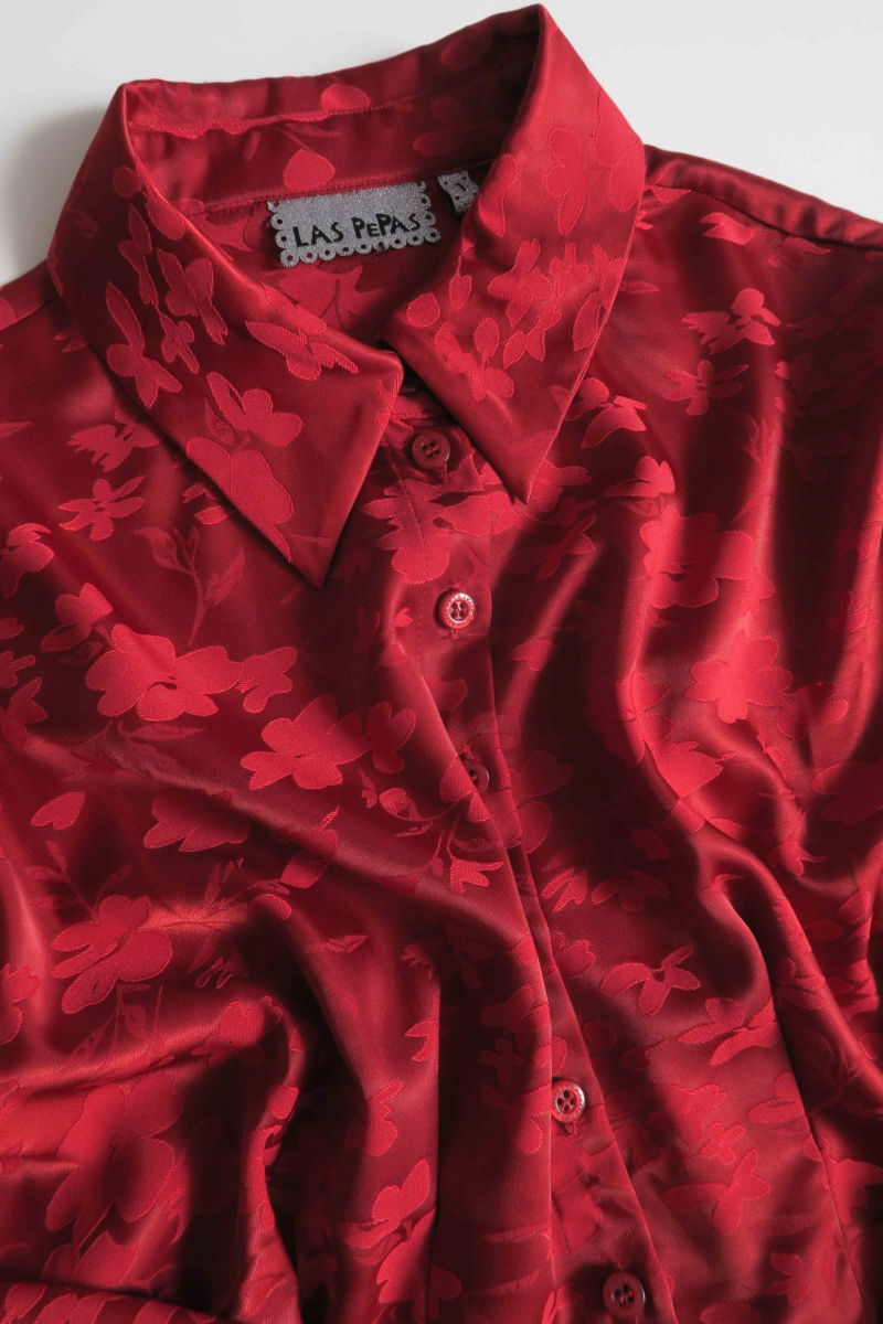 Camisa roja satinada de jacquard floreado con pinzas de entalle en frente y espalda, con lazo para regular. 