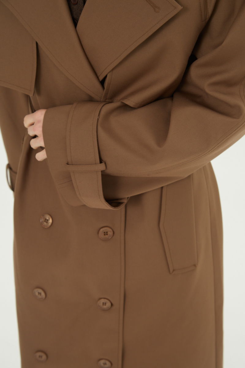 Trench sastrero largo con solapas amplias, charreteras en los hombros y cinturón.  
