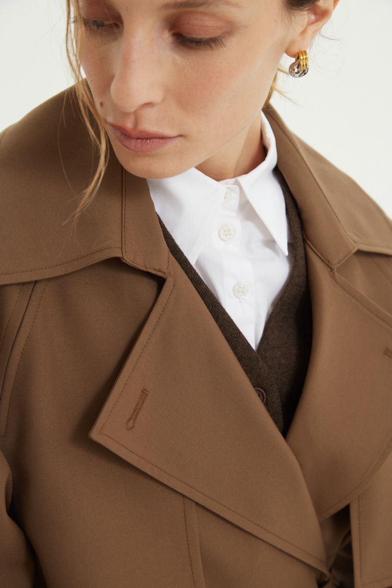 Trench sastrero largo con solapas amplias, charreteras en los hombros y cinturón.  
