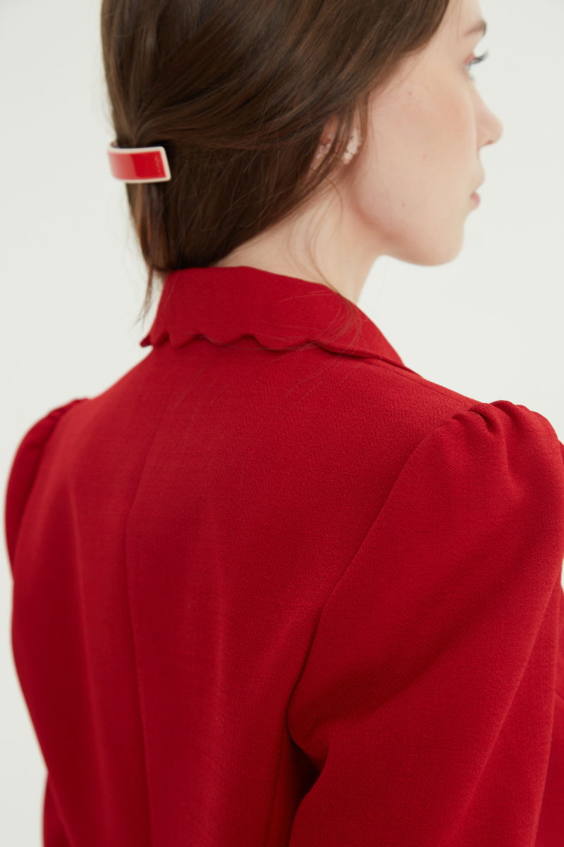 Blazer rojo sastrero entallado con terminación ondulada y mangas princesa. 
