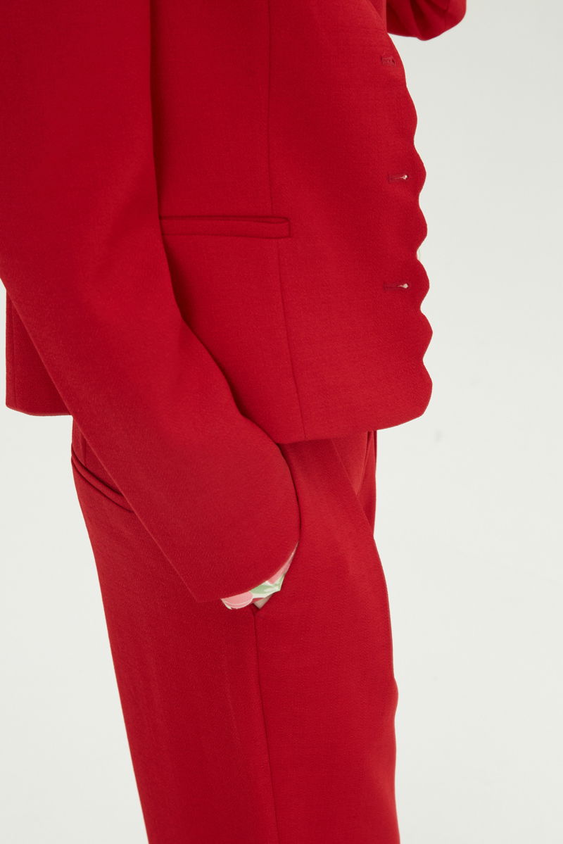 Blazer rojo sastrero entallado con terminación ondulada y mangas princesa. 
