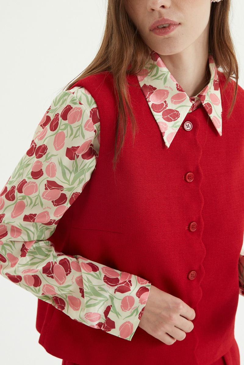 Chaleco rojo sastrero con terminación ondulada y botones a tono. 
