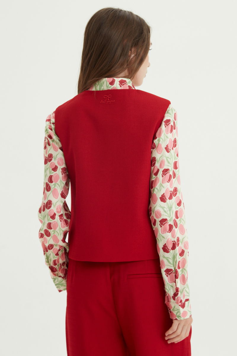 Chaleco rojo sastrero con terminación ondulada y botones a tono. 
