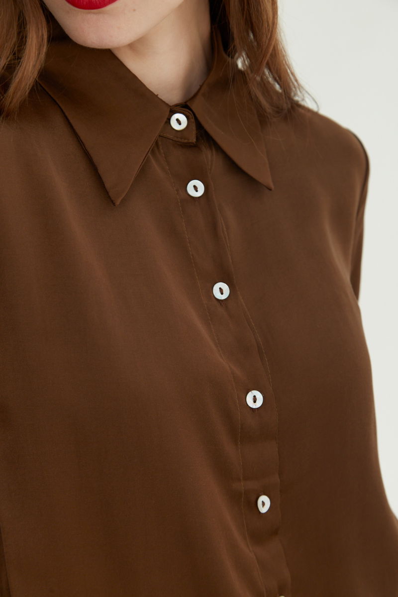 Camisa satinada con botones nacarados a contratono, de corte recto y larga hasta la cadera. 