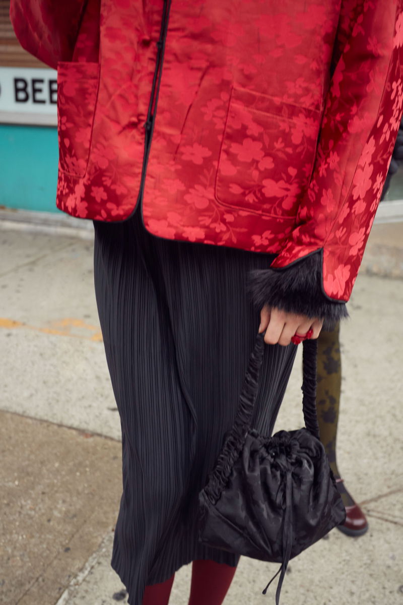 Falda negra midi plisada satinada con elástico en la cintura. Su fit es entallado, se estira y se adapta al cuerpo, con tajos laterales en el ruedo