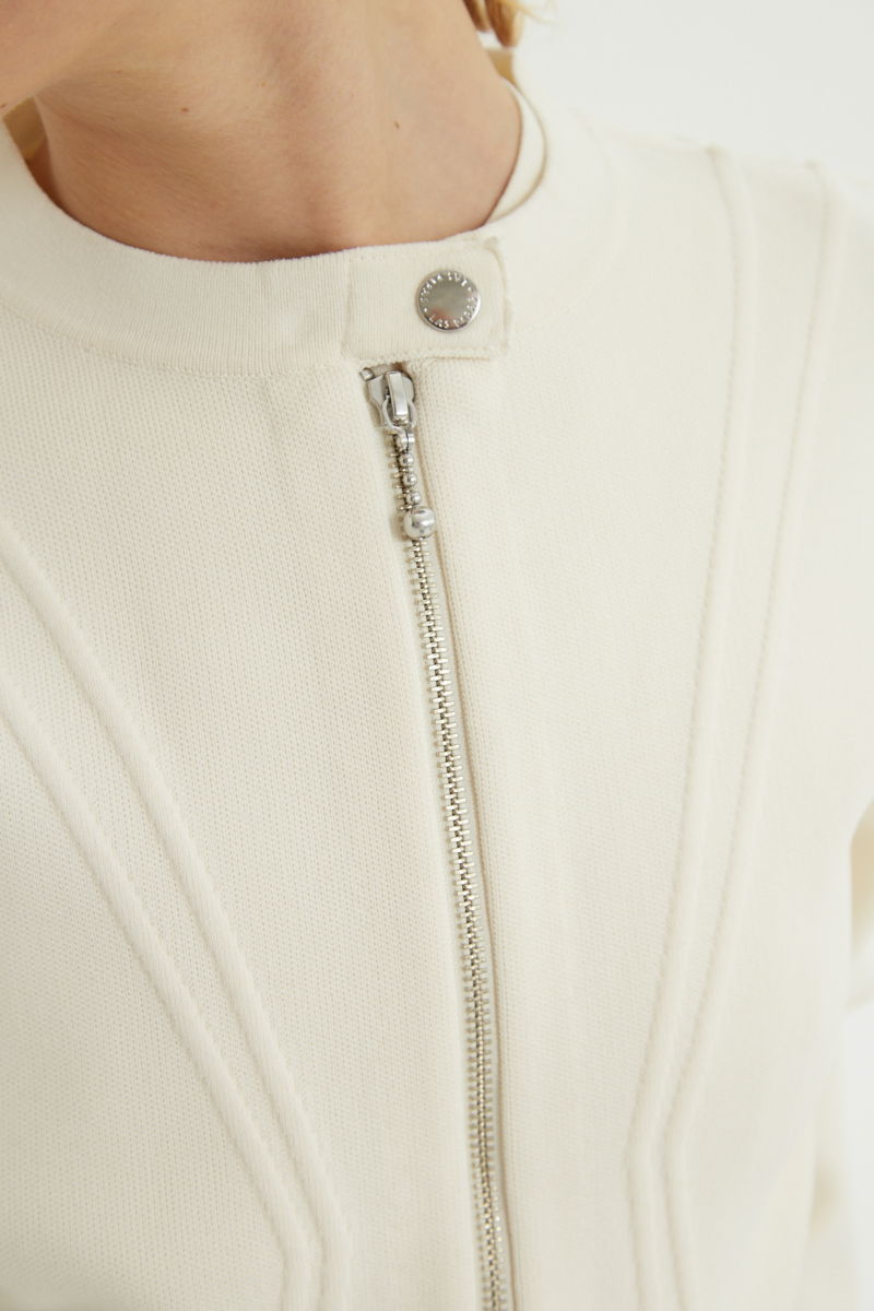 Campera crudo tejida estilo bomber larga a la cadera con cierre doble camino, cuello mao con broche snap, hombros anchos y terminación redondeada en el ruedo.