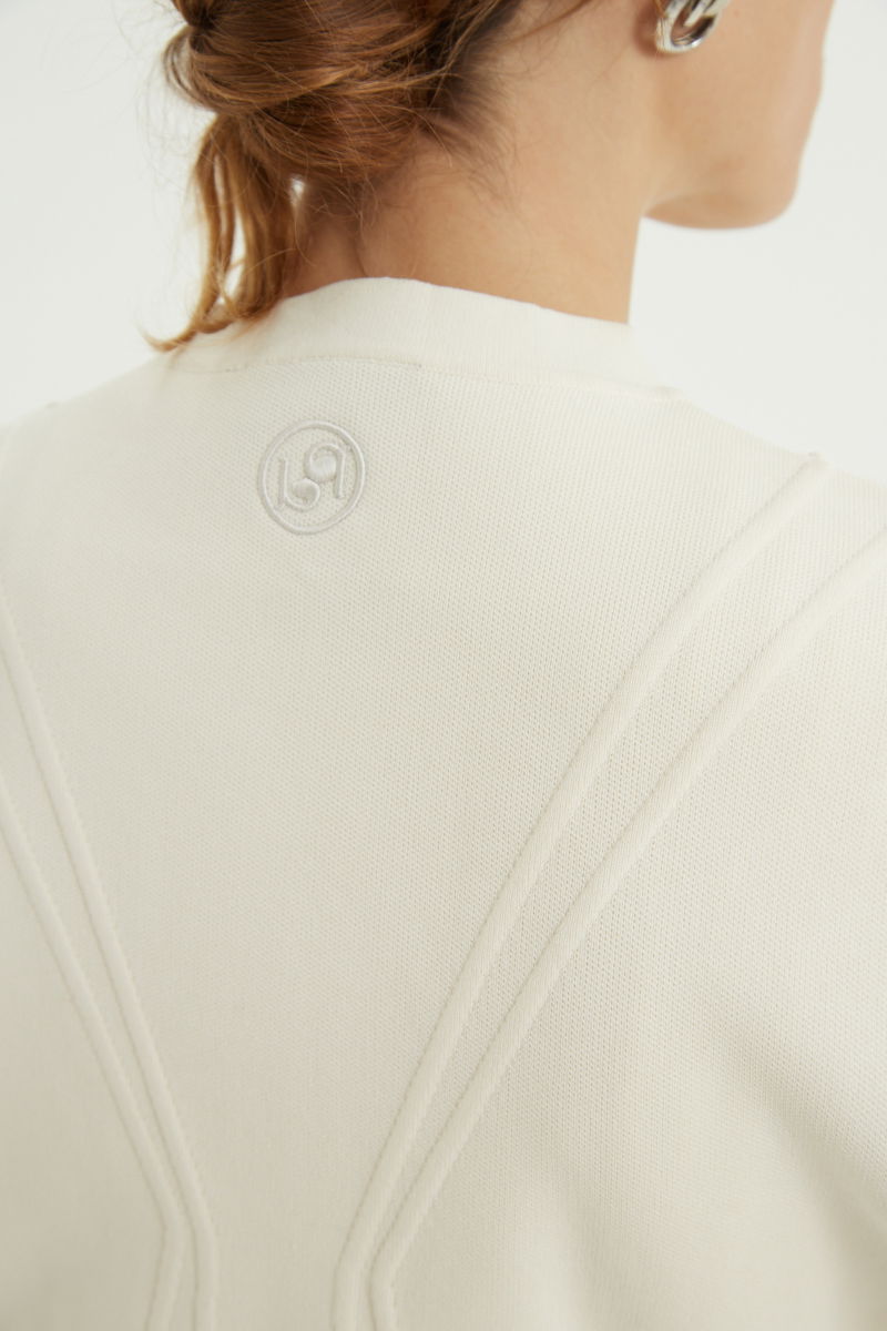 Campera crudo tejida estilo bomber larga a la cadera con cierre doble camino, cuello mao con broche snap, hombros anchos y terminación redondeada en el ruedo.