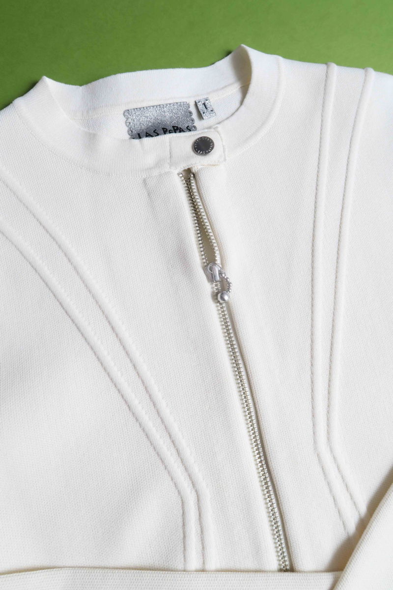 Campera crudo tejida estilo bomber larga a la cadera con cierre doble camino, cuello mao con broche snap, hombros anchos y terminación redondeada en el ruedo.