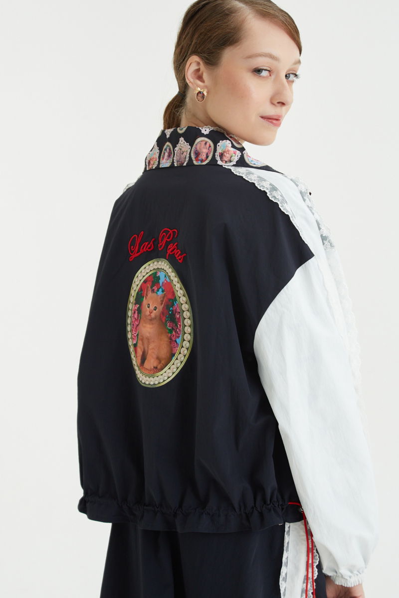 Campera reversible con puntilla y estampado de gatitos, cuello alto, broches snap y cintura con tancas.