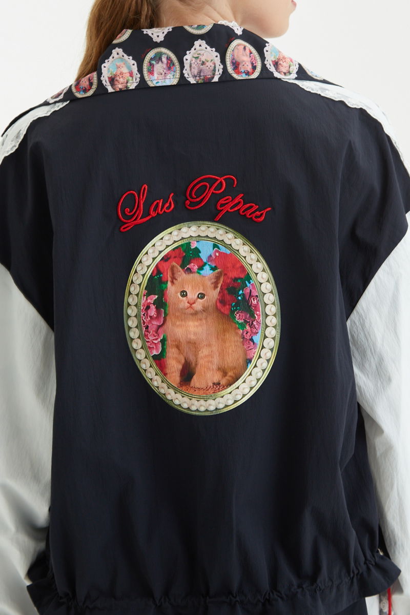 Campera reversible con puntilla y estampado de gatitos, cuello alto, broches snap y cintura con tancas.