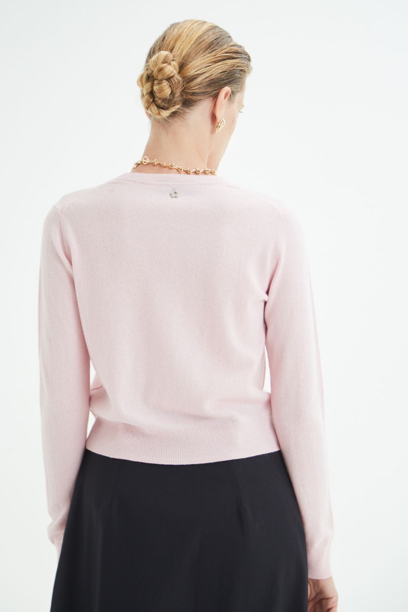 Cardigan rosa de lana y cachemira de corte recto entallado en la cintura con terminaciones en rib en puños y ruedo, cuello redondo cerrado y botones a tono.