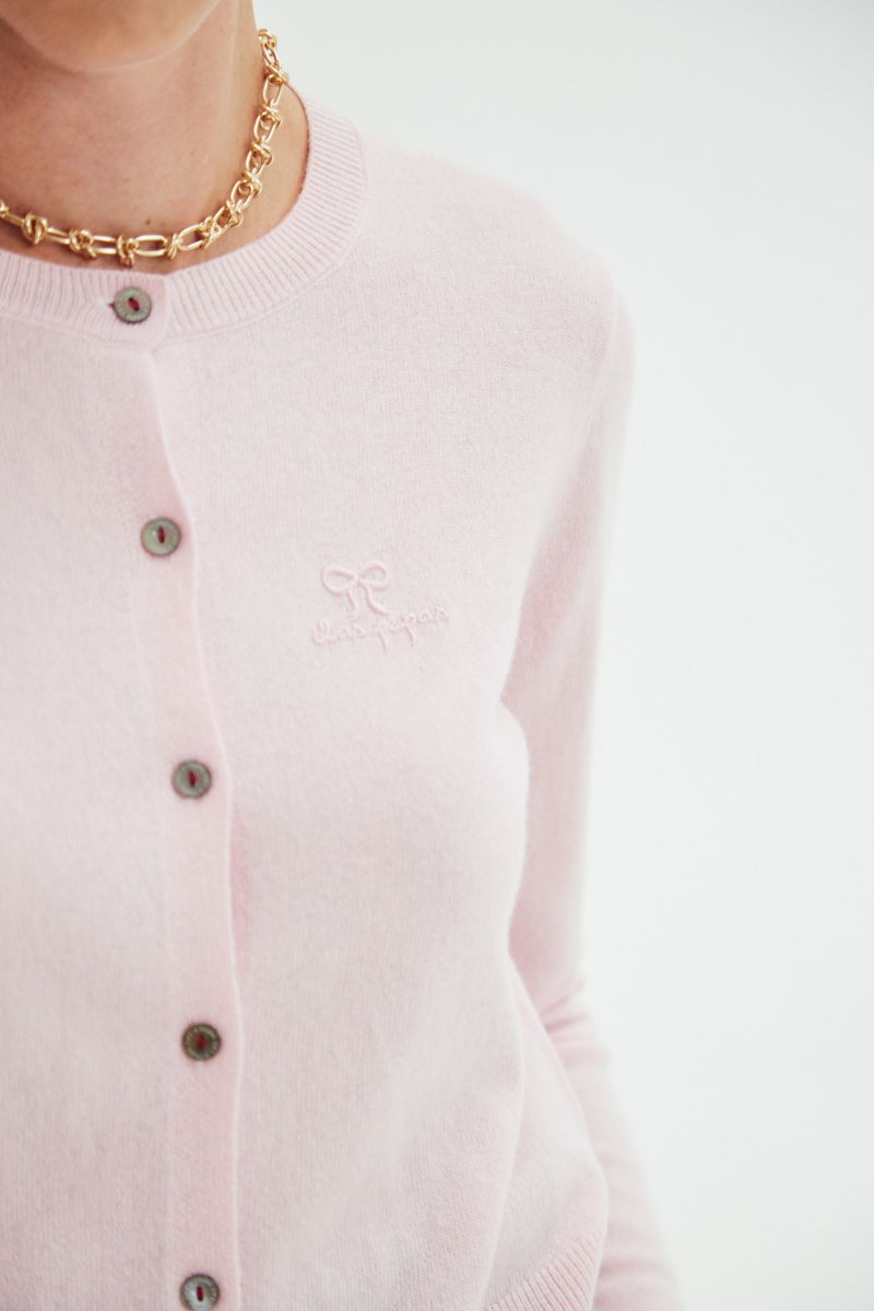 Cardigan rosa de lana y cachemira de corte recto entallado en la cintura con terminaciones en rib en puños y ruedo, cuello redondo cerrado y botones a tono.