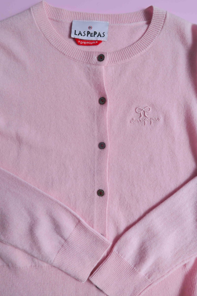 Cardigan rosa de lana y cachemira de corte recto entallado en la cintura con terminaciones en rib en puños y ruedo, cuello redondo cerrado y botones a tono.