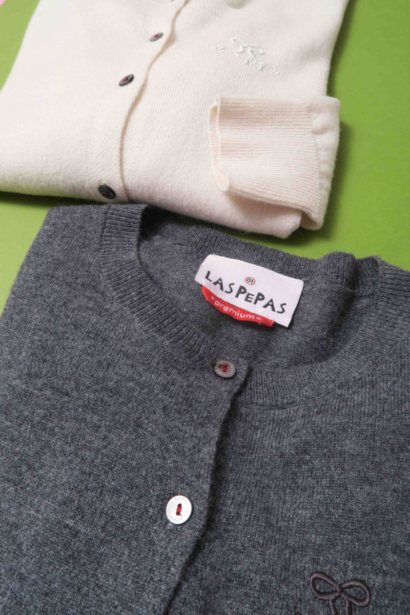 Cardigan gris de lana y cachemira de corte recto entallado en la cintura con terminaciones en rib en puños y ruedo, cuello redondo cerrado y botones a tono.