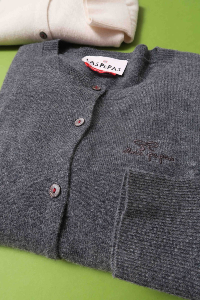 Cardigan gris de lana y cachemira de corte recto entallado en la cintura con terminaciones en rib en puños y ruedo, cuello redondo cerrado y botones a tono.