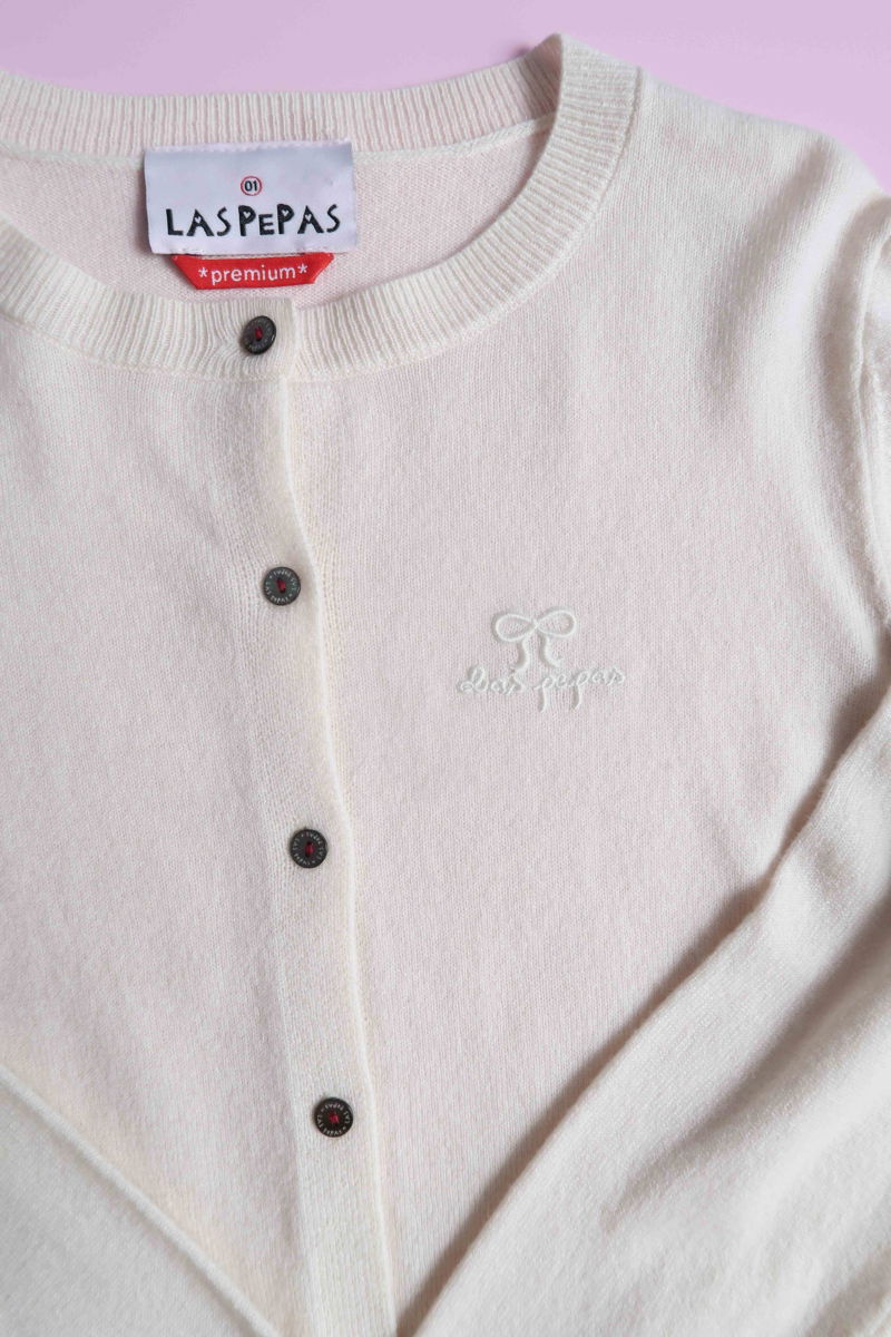 Cardigan crudo de lana y cachemira de corte recto entallado en la cintura con terminaciones en rib en puños y ruedo, cuello redondo cerrado y botones a tono.