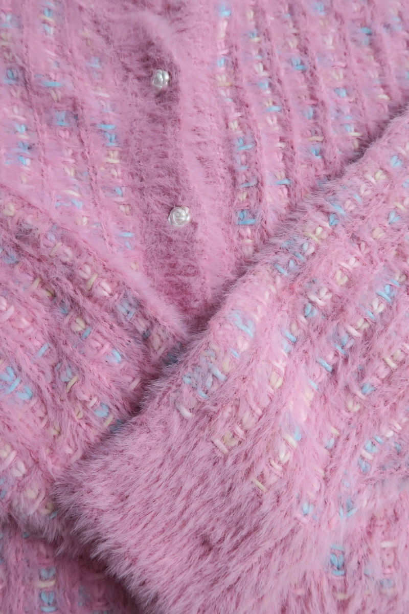 Saco tejido multicolor con textura de pelo y botones perlados en forma de flor. 
