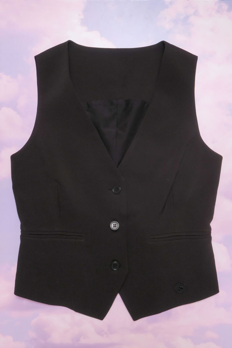 Chaleco negro sastrero largo a la cadera con botones a tono, bolsillos ojal y pinzas en frente y espalda. 
