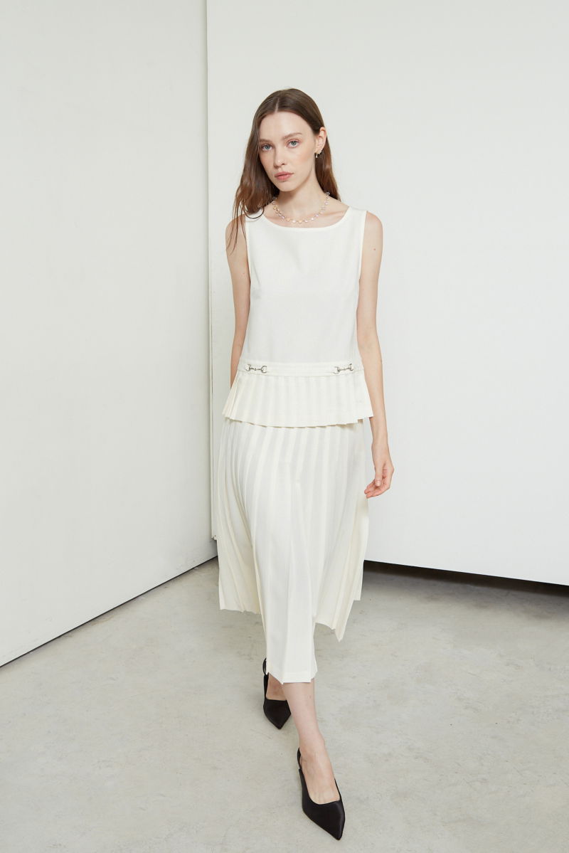 Blusa cruda sastrera sin mangas con tablas en la cintura, herrajes metálicos y escote a la base del cuello, larga a la cadera. 