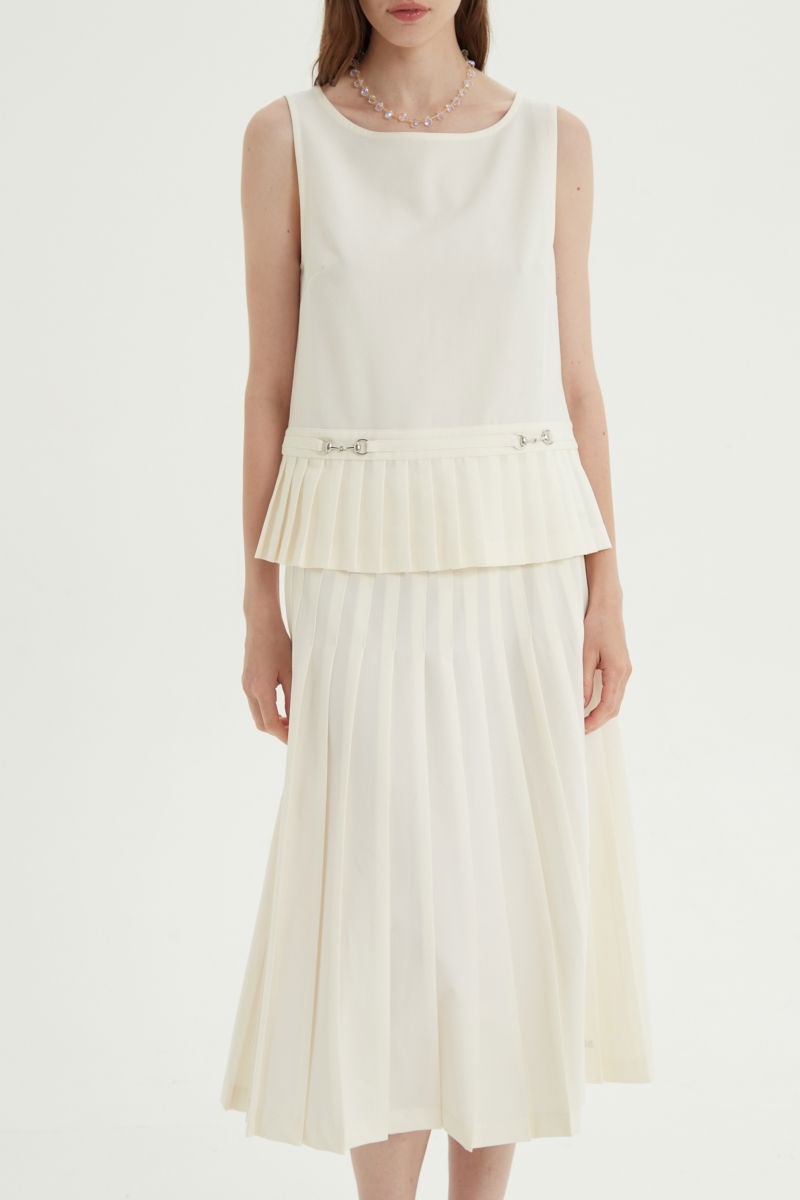 Blusa cruda sastrera sin mangas con tablas en la cintura, herrajes metálicos y escote a la base del cuello, larga a la cadera. 